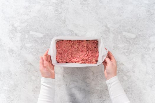 Flat lay. Preparing classic meatloaf in a loaf pan lined with parchment paper.
