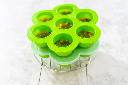 Filling silicone molds with egg mixture to make egg bites in a pressure cooker.