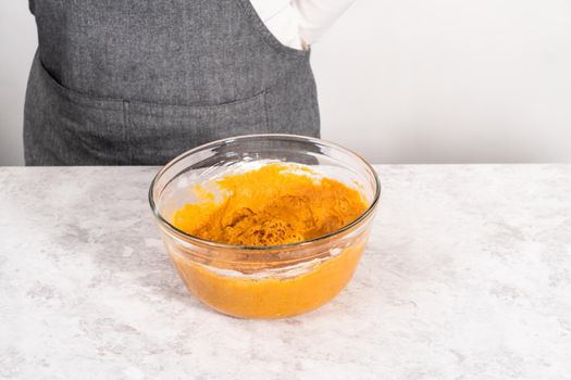 Mixing ingredients in a glass mixing bowl to bake sweet pumpkin bread.