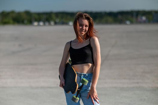 Young caucasian woman holding a long board outdoors