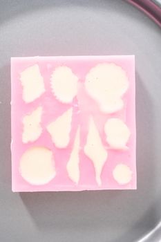 Filling in chocolate silicone molds with melted chocolate to preparing mini mermaid chocolate bars.