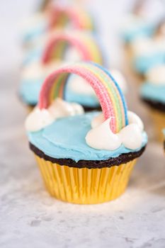 Chocolate cupcakes decorated with blue buttercream frosting and rainbow for unicorn theme birthday party.