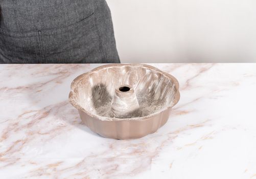 Greasing bunt cake pan to bake apple bundt cake with caramel glaze.
