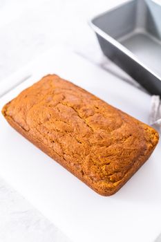 Sliced homemade pumpkin bread on a white cutting board.