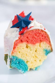 Slice of July 4th bundt cake covered with a vanilla glaze and decorated with chocolate stars.