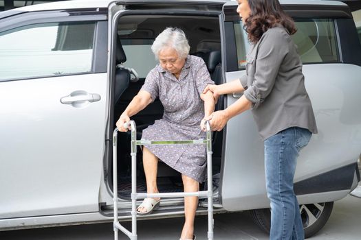 Caregiver daughter help and support asian senior or elderly old lady woman patient prepare get out her car.