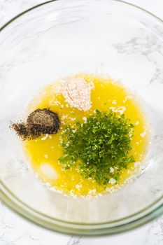 Mixing ingredients in a glass mixing bowl to prepare butter mixture for garlic lobster tails.