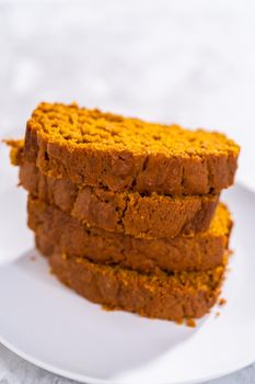 Stack of homemade pumpkin bread slices on a white plate.