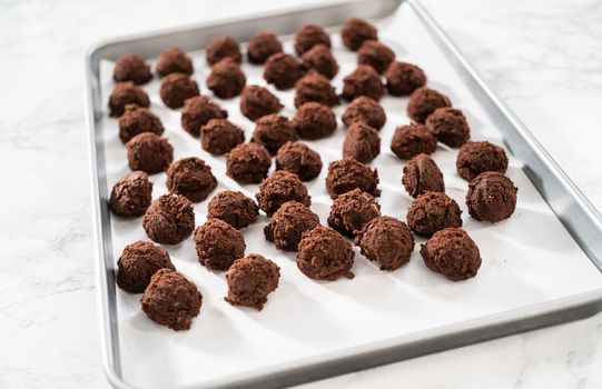 Scooping cookie dough with a small dough scoop into a baking sheet lined with parchment paper to bake peppermint white chocolate cookies.