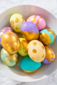 Colored and painted with gold hard-boiled eggs on a marble background.