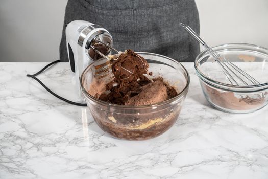 Mixing ingredients in a large glass mixing bowl to bake peppermint white chocolate cookies.