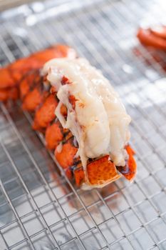 Buttering lobster tails on a baking sheet with kitchen foil.