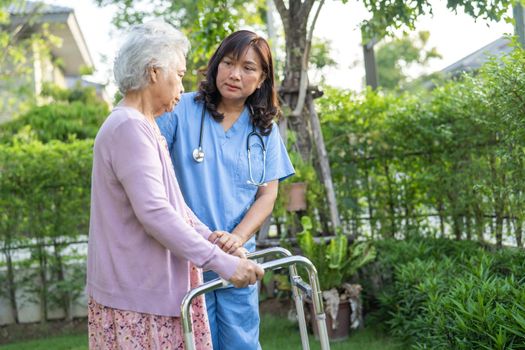 Doctor help and care Asian senior or elderly old lady woman use walker with strong health while walking at park in happy fresh holiday.