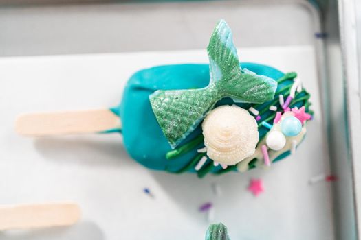 Mermaid cakesicles with drizzled chocolate, chocolate mermaid tails, seashells, and sprinkles.