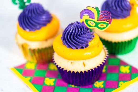 Mardi Gras vanilla cupcakes in foil cupcake cups and decorated with Italian buttercream frosting.