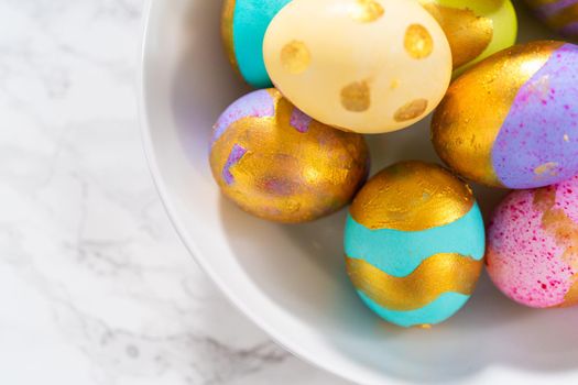 Colored and painted with gold hard-boiled eggs on a marble background.