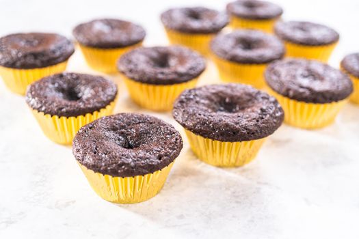 Cooling freshly baked chocolate cupcakes to be decorated with buttercream frosting.