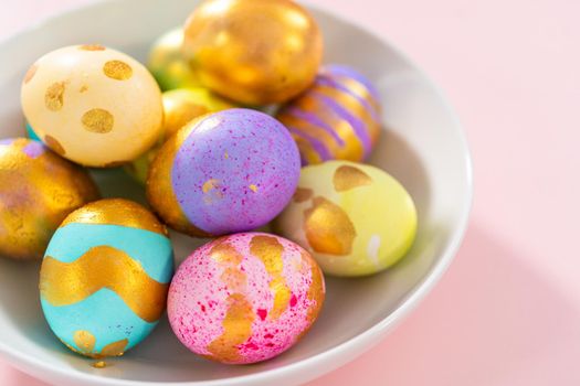 Colored and painted with gold hard-boiled eggs on a pink background.