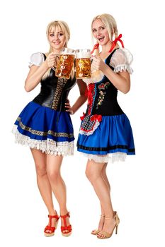 Full length portrait of a two blond womans with traditional costume Dirndl holding beer glasses isolated on white background. Oktoberfest