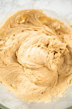 Mixing ingredients in a large glass mixing bowl to bake banana oatmeal muffins.