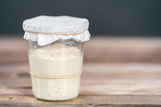 Feeding sourdough starter in a glass mason jar for baking artisan bread.