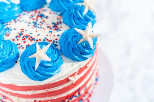 Decorating chocolate cake with white, red, and blue buttercream frosting for July 4th celebration.