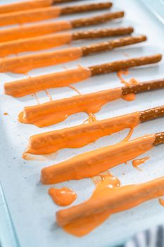 Dipped in chocolate pretzel rods on a baking sheet with parchment paper.