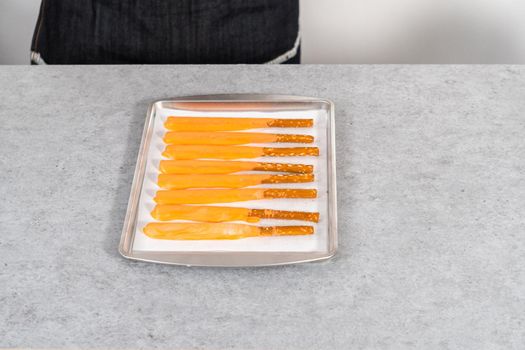 Dipped in chocolate pretzel rods on a baking sheet with parchment paper.