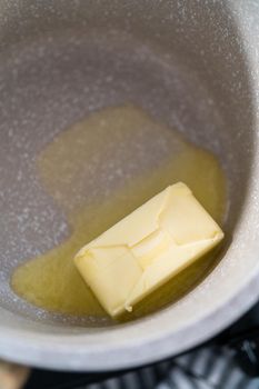 Melting stick of unsalted butter in a small saucepan.
