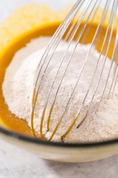 Mixing ingredients in a glass mixing bowl to bake sweet pumpkin bread.