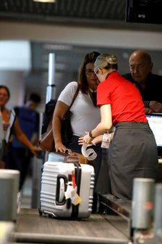 salvador, bahia, brazil - july 27, 2018: an airline attendant weighs a suitcase on a conveyor belt at check-in at the airport in the city of Salvador.