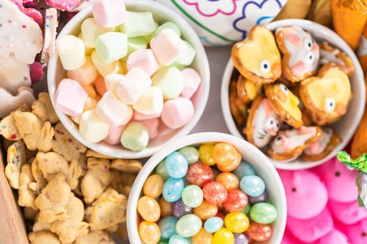 Assembling charcuterie board with Easter candies, cookies, and marshmallows.