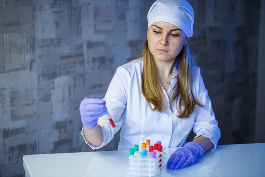 A medical professional, laboratory assistant, doctor performs an analysis in a laboratory, uses test tubes, a pipette and a petri dish for the presence of bacteria in the human body. Selective focus