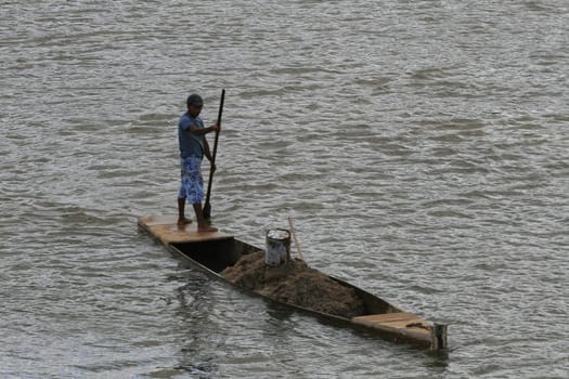 itamaraju , bahia, brazil - september 3, 2008: Person using a canoe collects sand from the Jucurucu river bed in the city of Itamaraju.