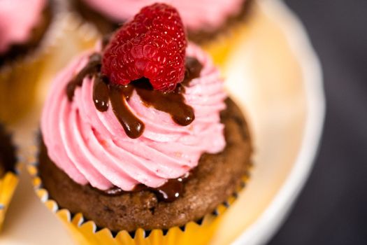 Gourmet chocolate raspberry cupcakes drizzled with chocolate ganache and topped with a fresh raspberry.