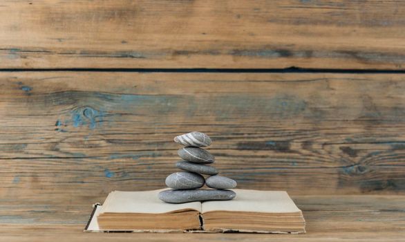 books and stack of zen stones on wood table background. Feng Shui, Balance and relaxation concept. 