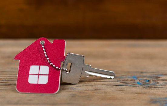 House keys with house shaped keychain on wooden background