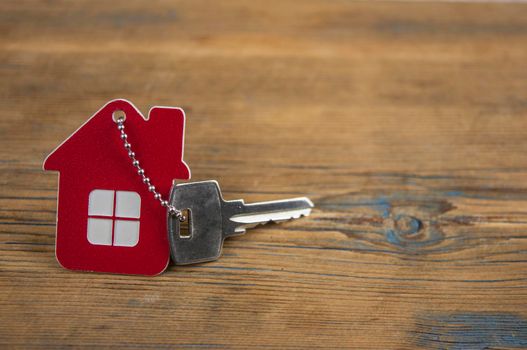 House keys with house shaped keychain on wooden background