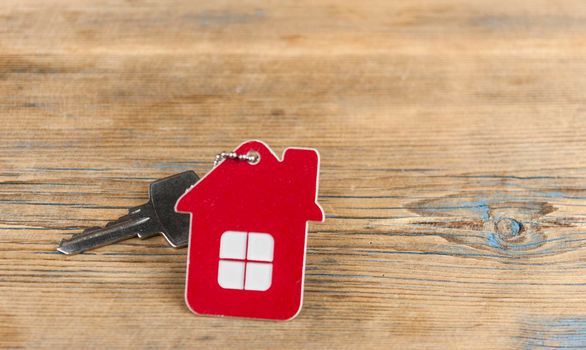 House keys with house shaped keychain on wooden background