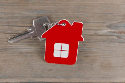 House keys with house shaped keychain on wooden background