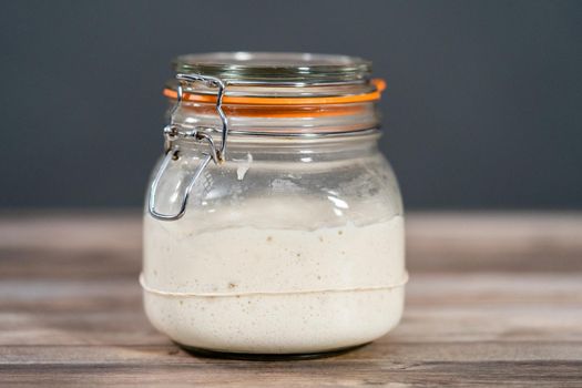 Feeding sourdough starter in a glass mason jar for baking artisan bread.