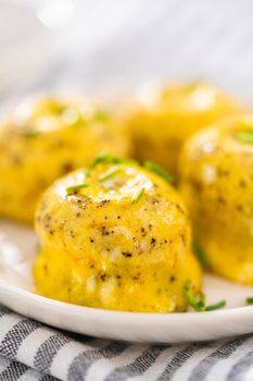 Serving egg bites garnished with fresh chives on a white plate.