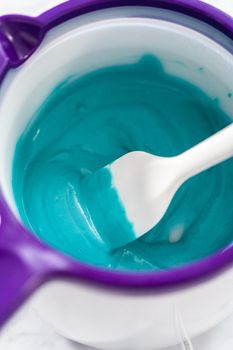 Melting chocolate melts in an electric chocolate melting pot to preparing mini mermaid chocolate bars.
