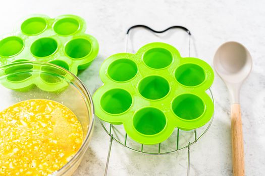 Filling silicone molds with egg mixture to make egg bites in a pressure cooker.