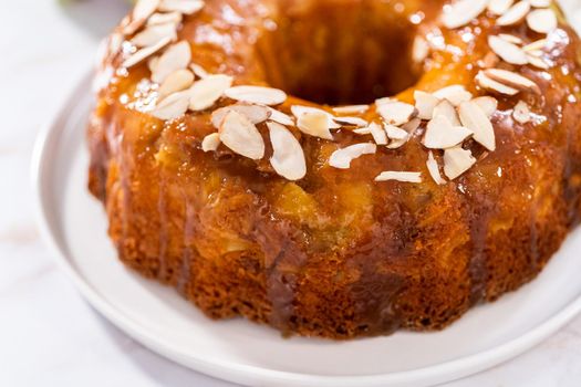 Freshly baked apple bundt cake with caramel glaze on a white plate.