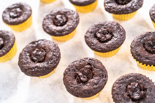 Filling in chocolate cupcakes with chocolate ganache.