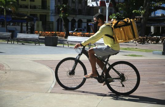 Jovem com uma mochila entregando comida em uma bicicleta na cidade de Salvador, nessa sexta-feira (13) (Joá Souza/ Futura Press). 