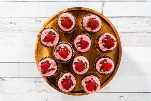 Flat lay. Gourmet chocolate raspberry cupcakes drizzled with chocolate ganache and topped with a fresh raspberry.