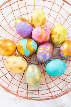 Colored and painted with gold hard-boiled eggs on a marble background.