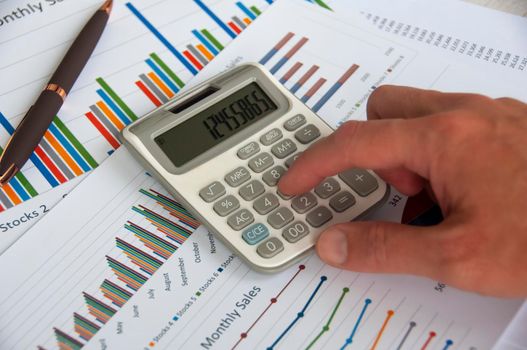 Hand pressing calculator with graph analysis background. Business analysis concept.